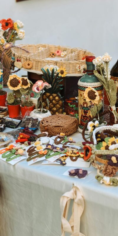 Colorful market table displaying handcrafted items including woven baskets, ceramics, and decorations.